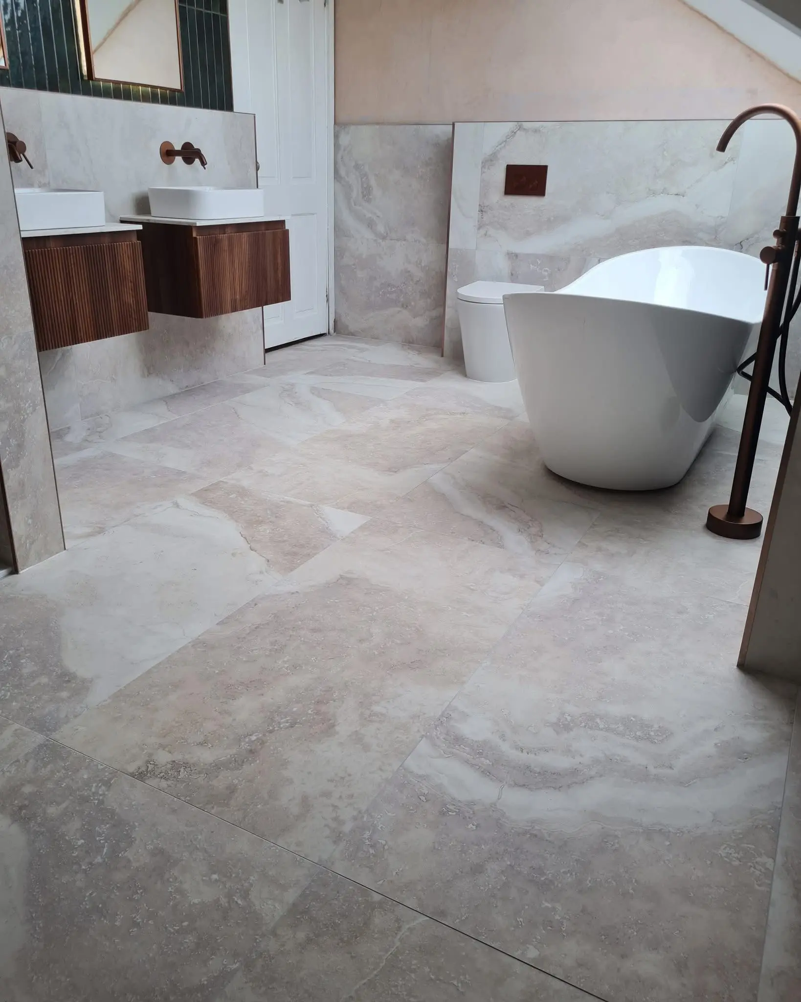 Bathroom fitter Barnet - freestanding bath with travertine floor tiles and wall-hung vanity unit