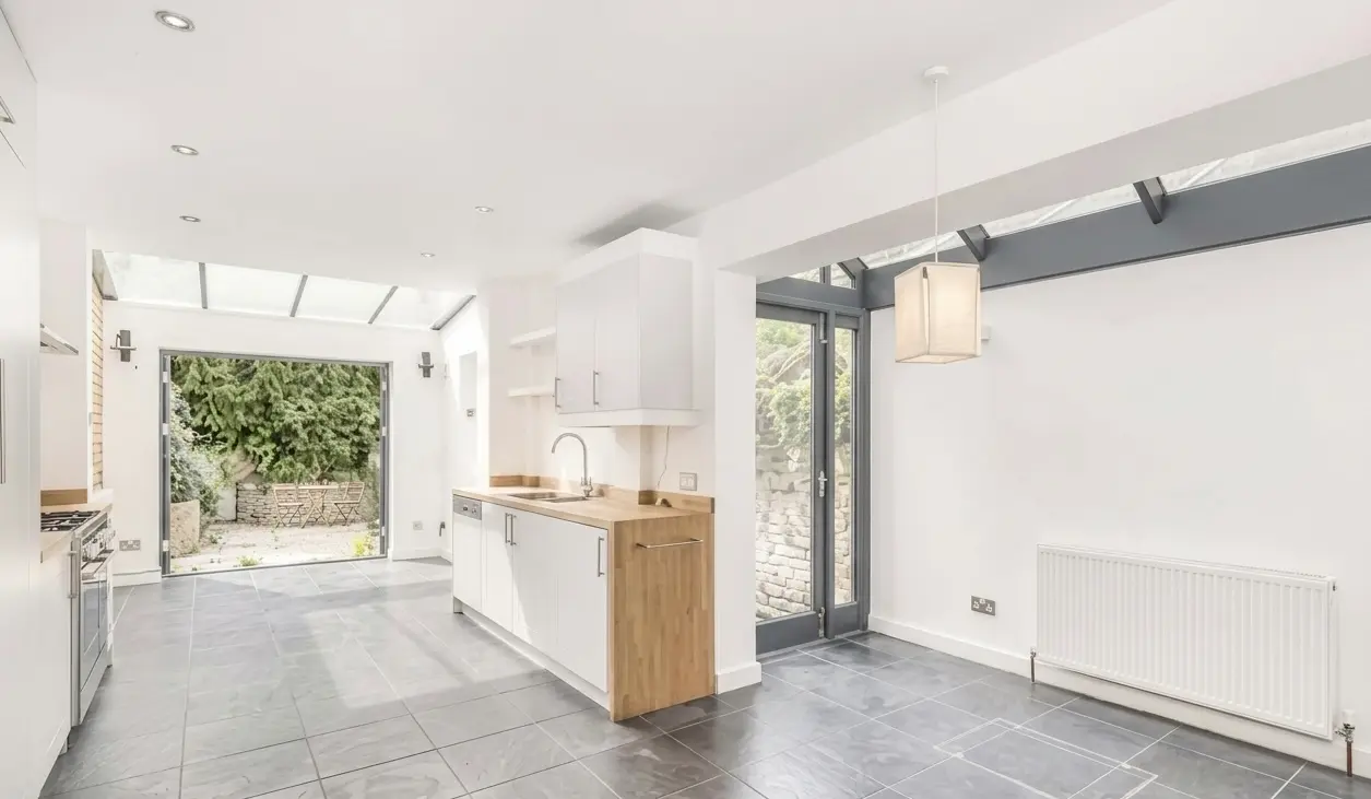 Kitchen renovation North London white cabinets with bifold doors and garden view — Resale Refurbs Ltd