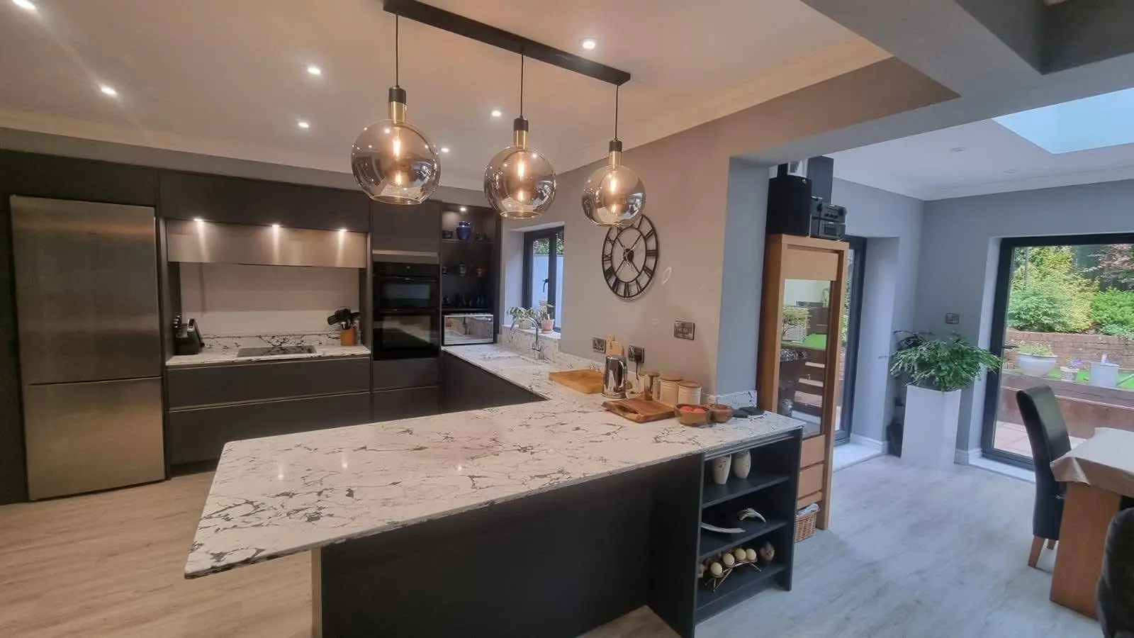 Kitchen renovation Enfield dark handleless units with marble quartz island and pendant lights - Resale Refurbs Ltd